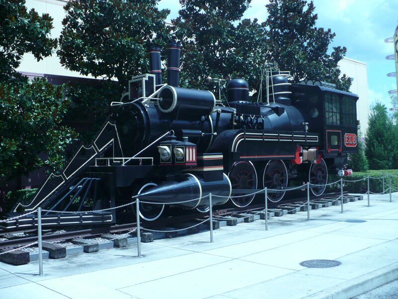 Black Steam Locomotive — Calm, Afternoon, Photograph, Train Tracks, Trees, Building