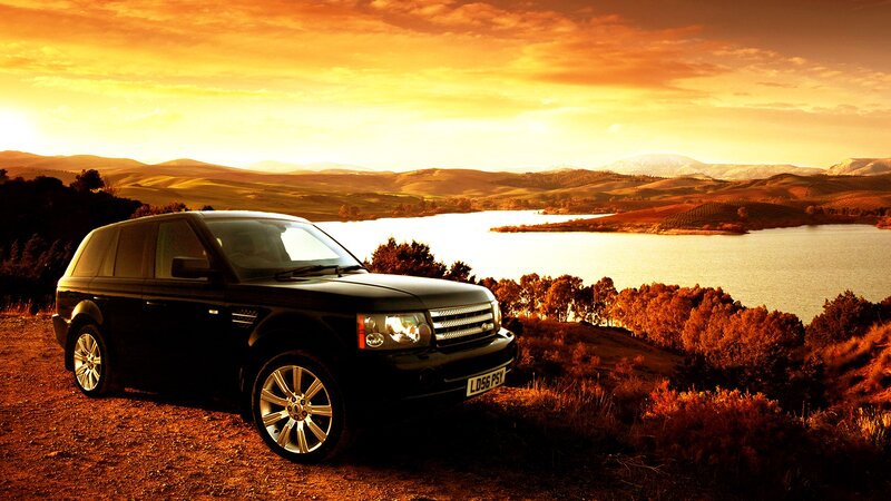 Black SUV at sunset by lake