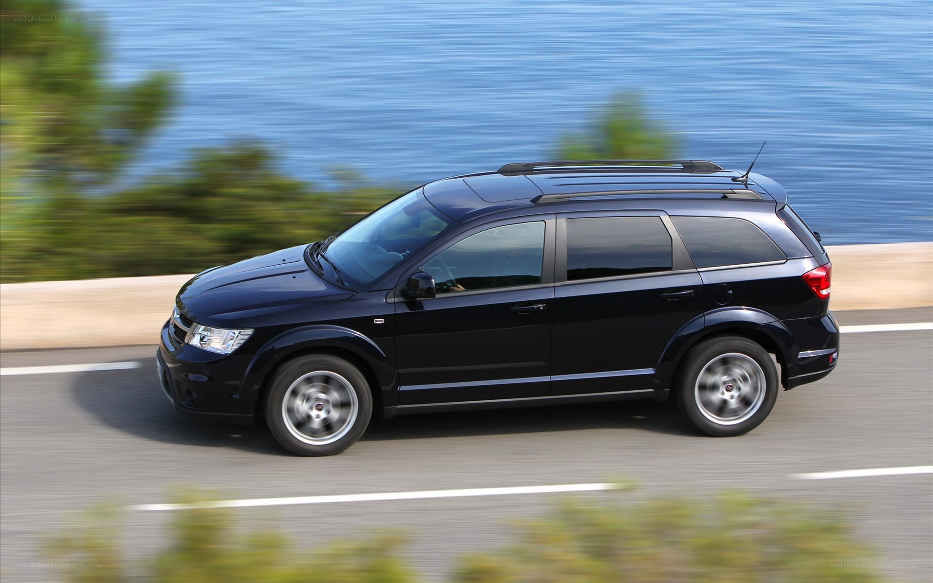 black suv driving on coastal road