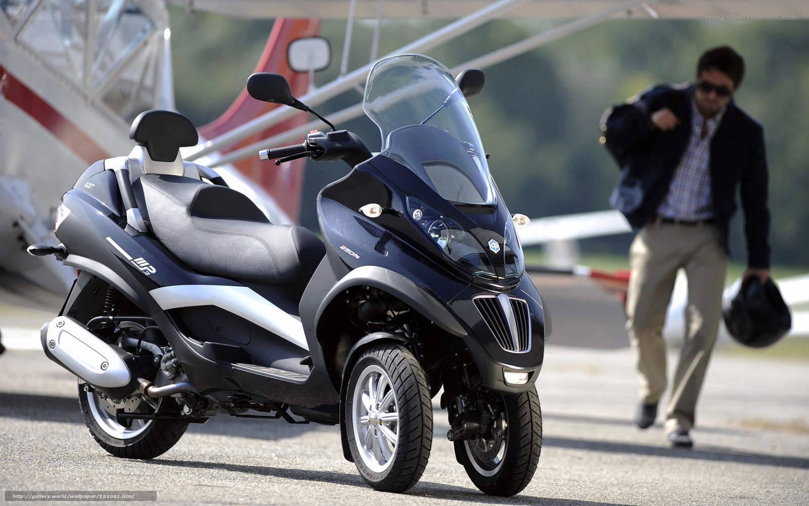 Black three-wheeled scooter on tarmac