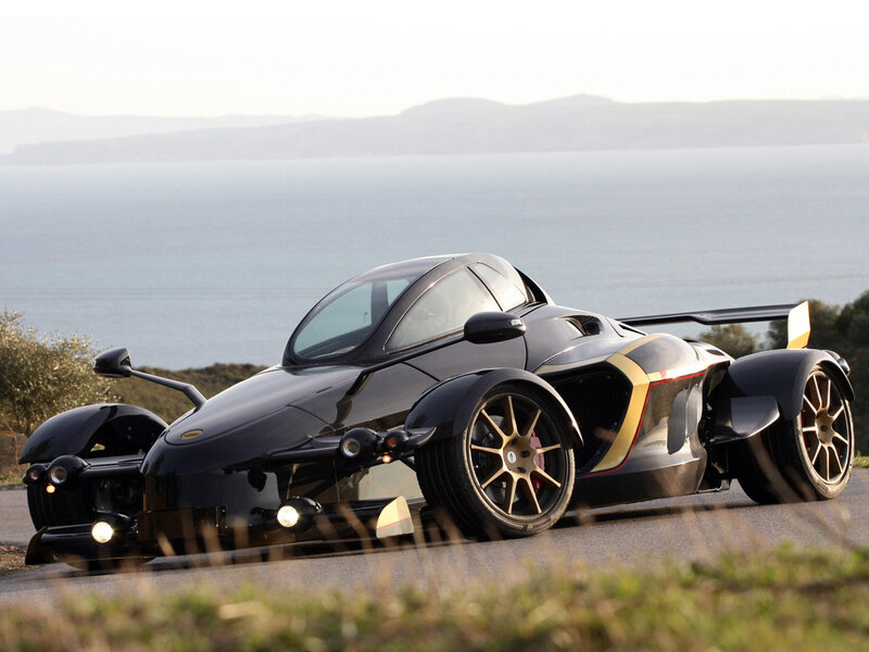 Black three-wheeled sports car on coastal road
