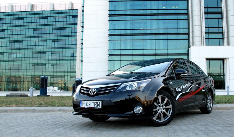 Black Toyota Avensis in front of building