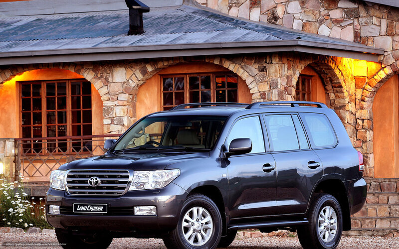Black Toyota Land Cruiser in front of stone house