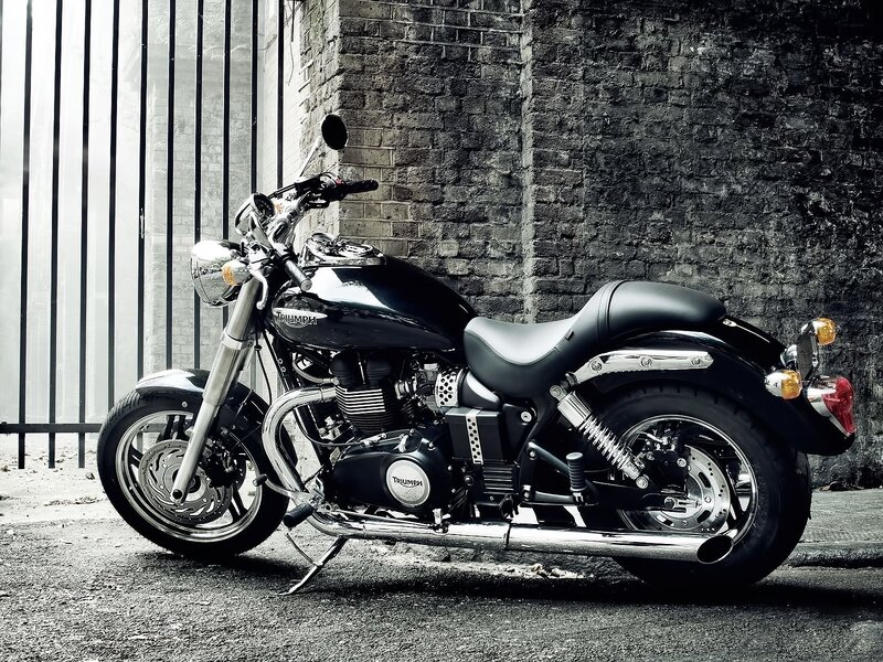 Black Triumph motorcycle against brick wall