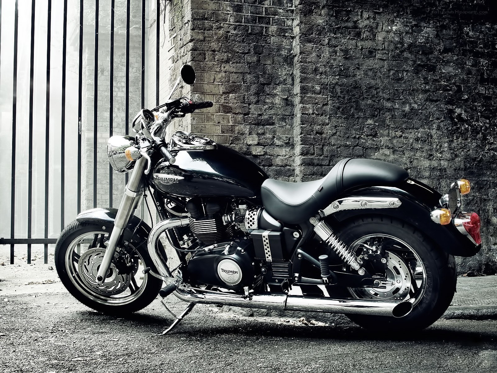 Black Triumph motorcycle against brick wall