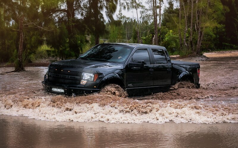 Black truck driving through floodwaters