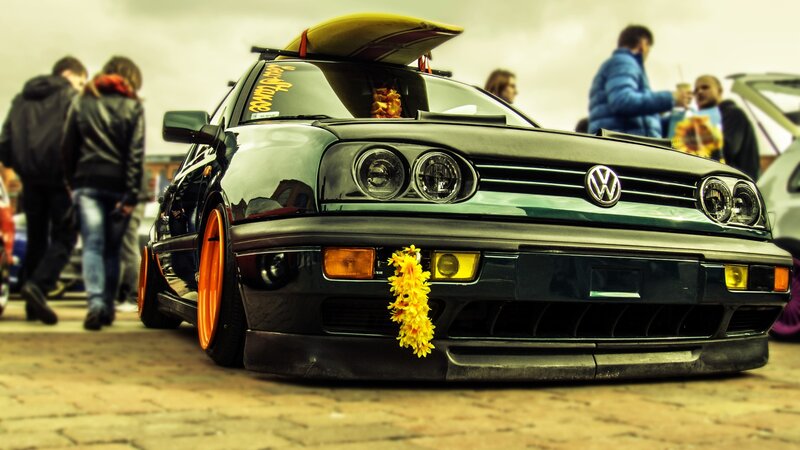 Black VW with surfboard on roof