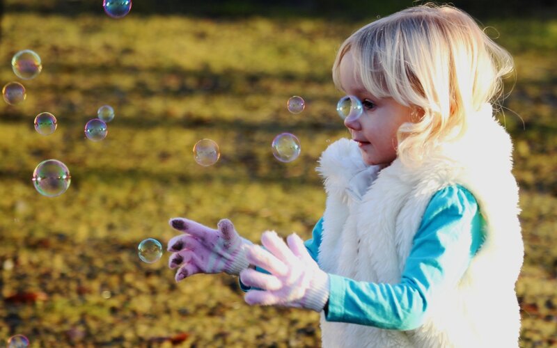 Blonde Child Playing with Bubbles