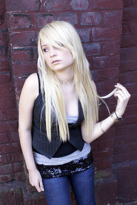 blonde woman against brick wall