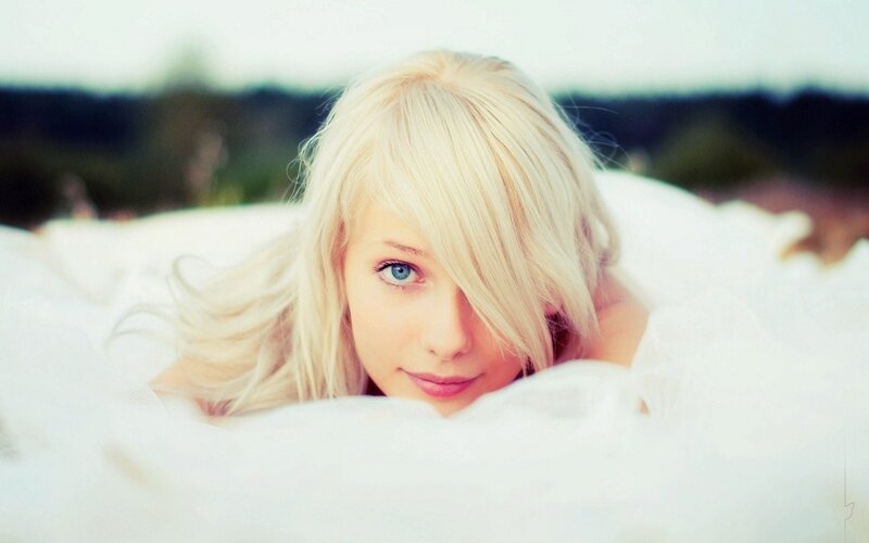 blonde woman lying on white fabric