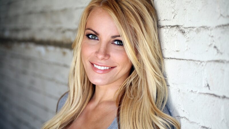 blonde woman smiling against brick wall