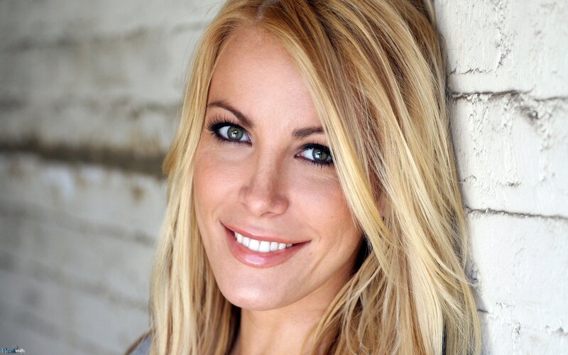 blonde woman smiling against brick wall