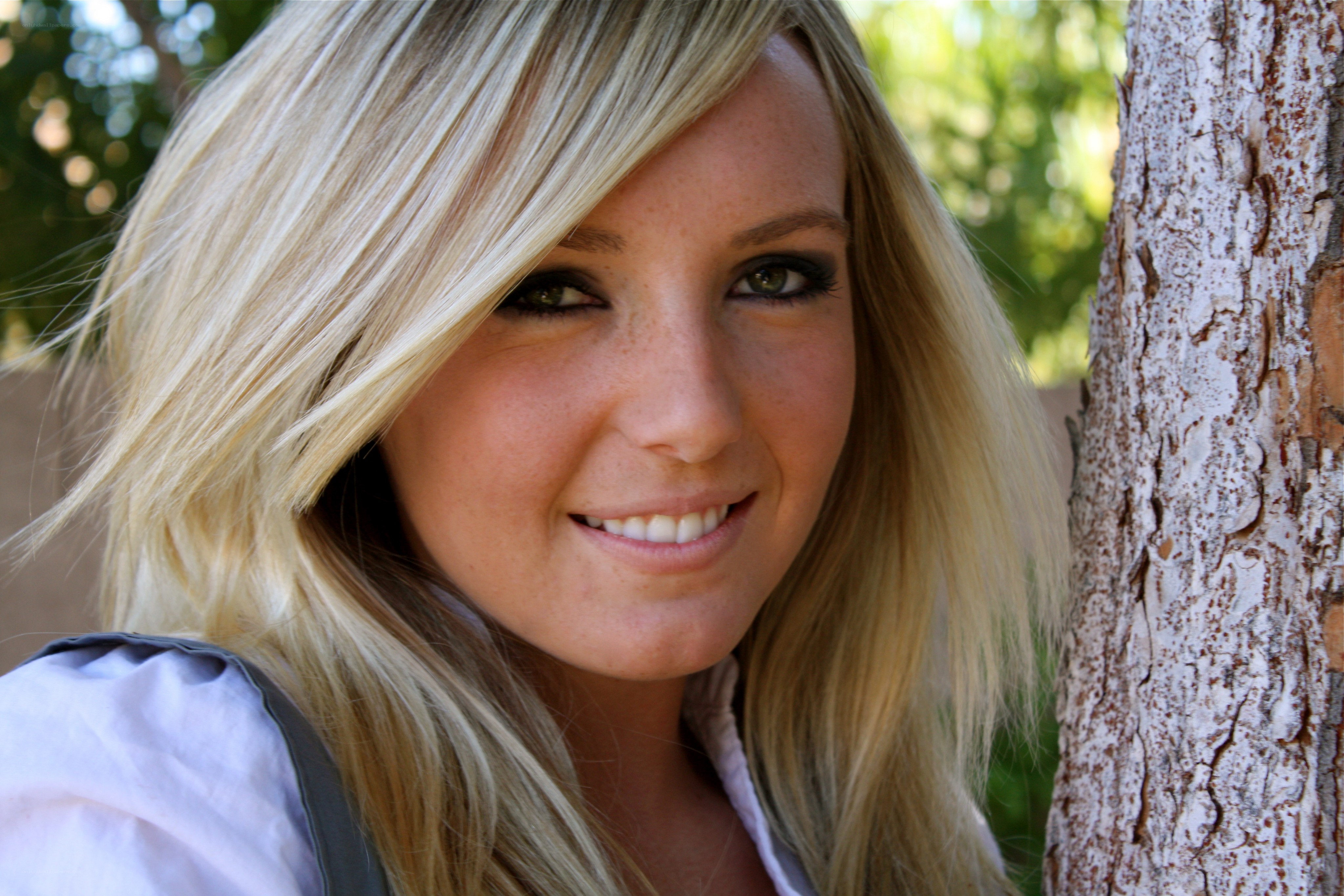 blonde woman smiling by tree