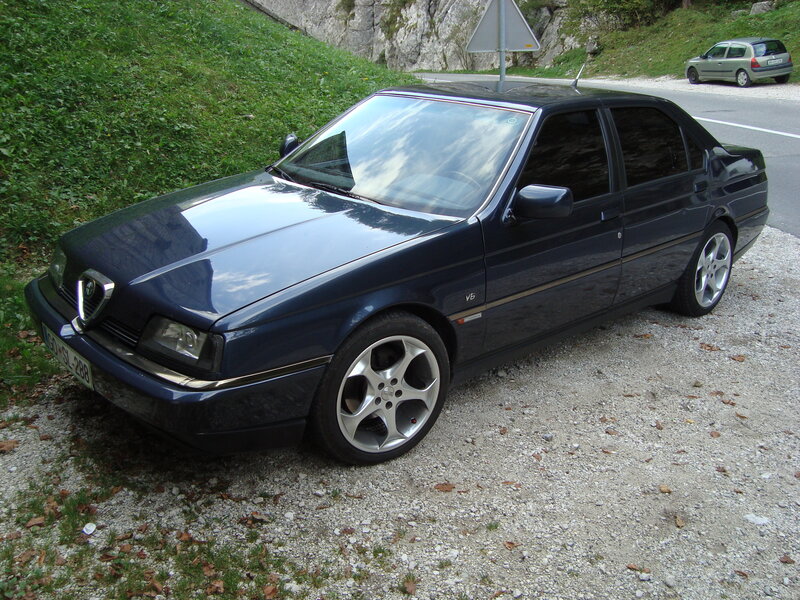 Blue Alfa Romeo parked on gravel
