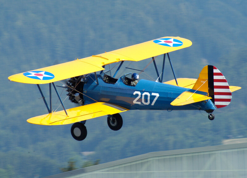 blue and yellow biplane in flight