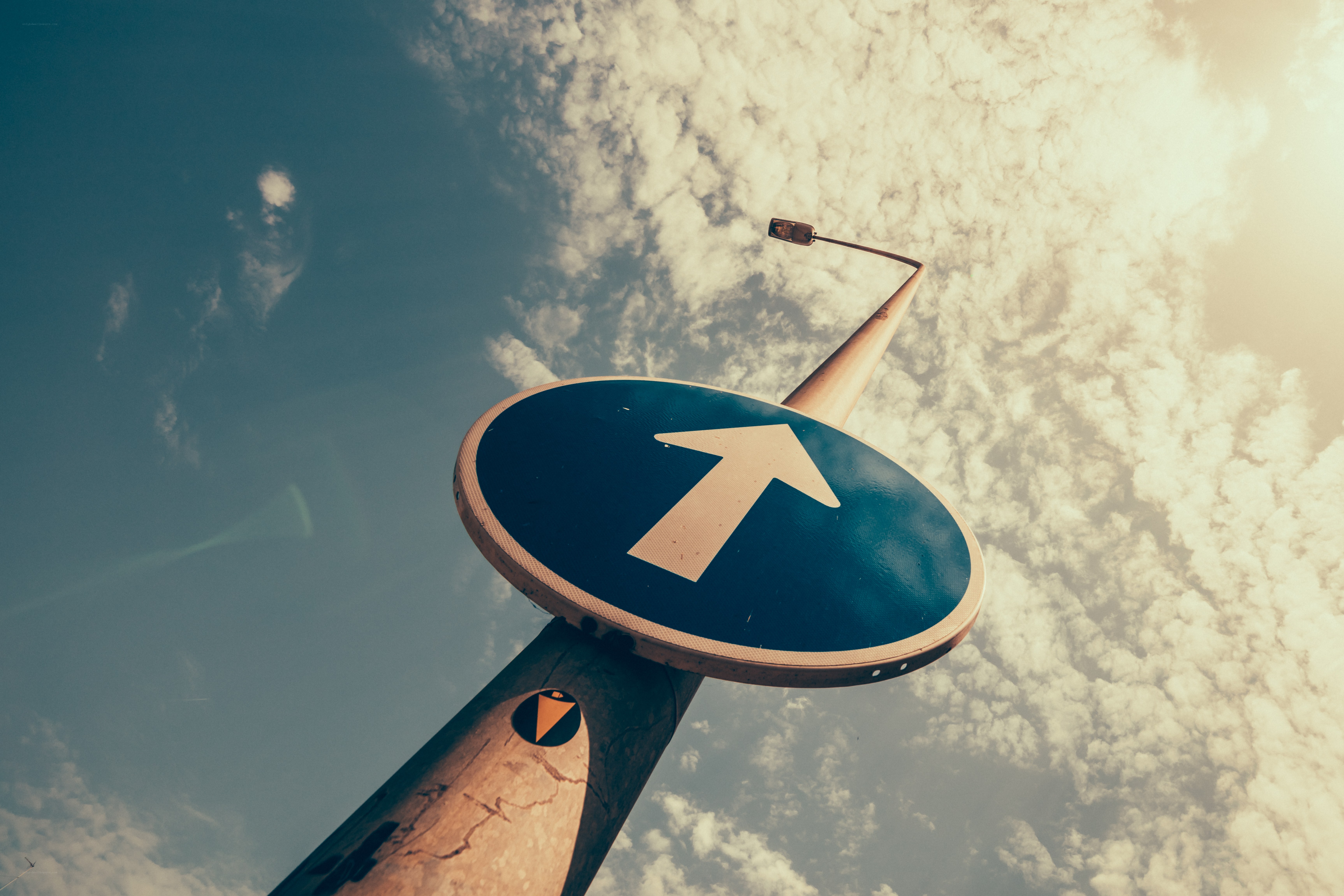 Blue arrow sign against sky