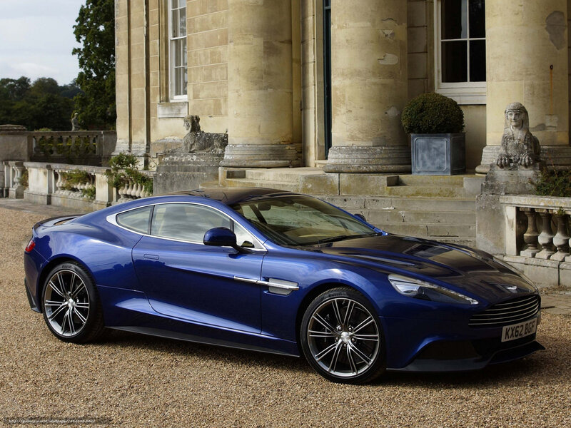 Blue Aston Martin in front of mansion