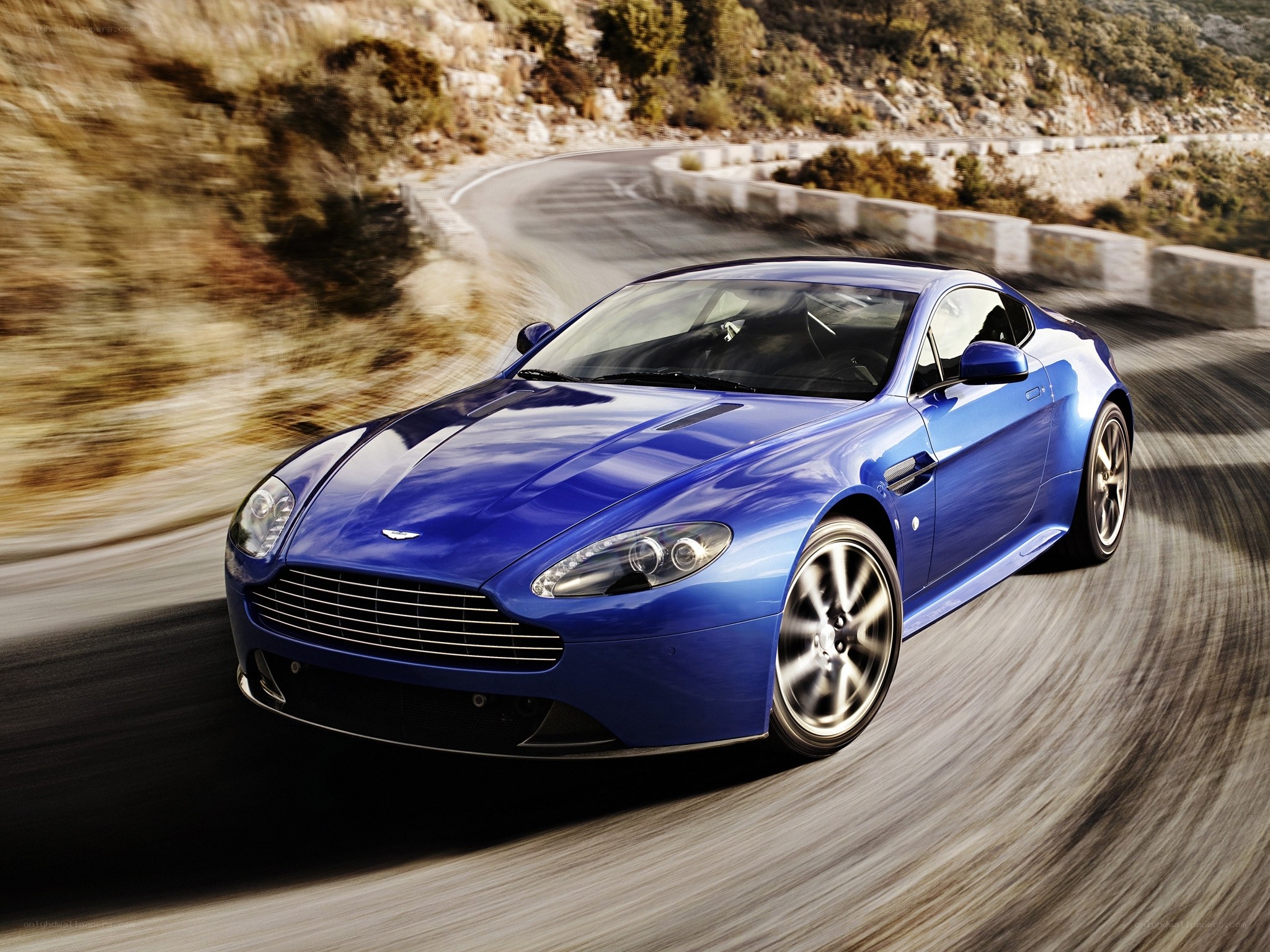 Blue Aston Martin on winding road