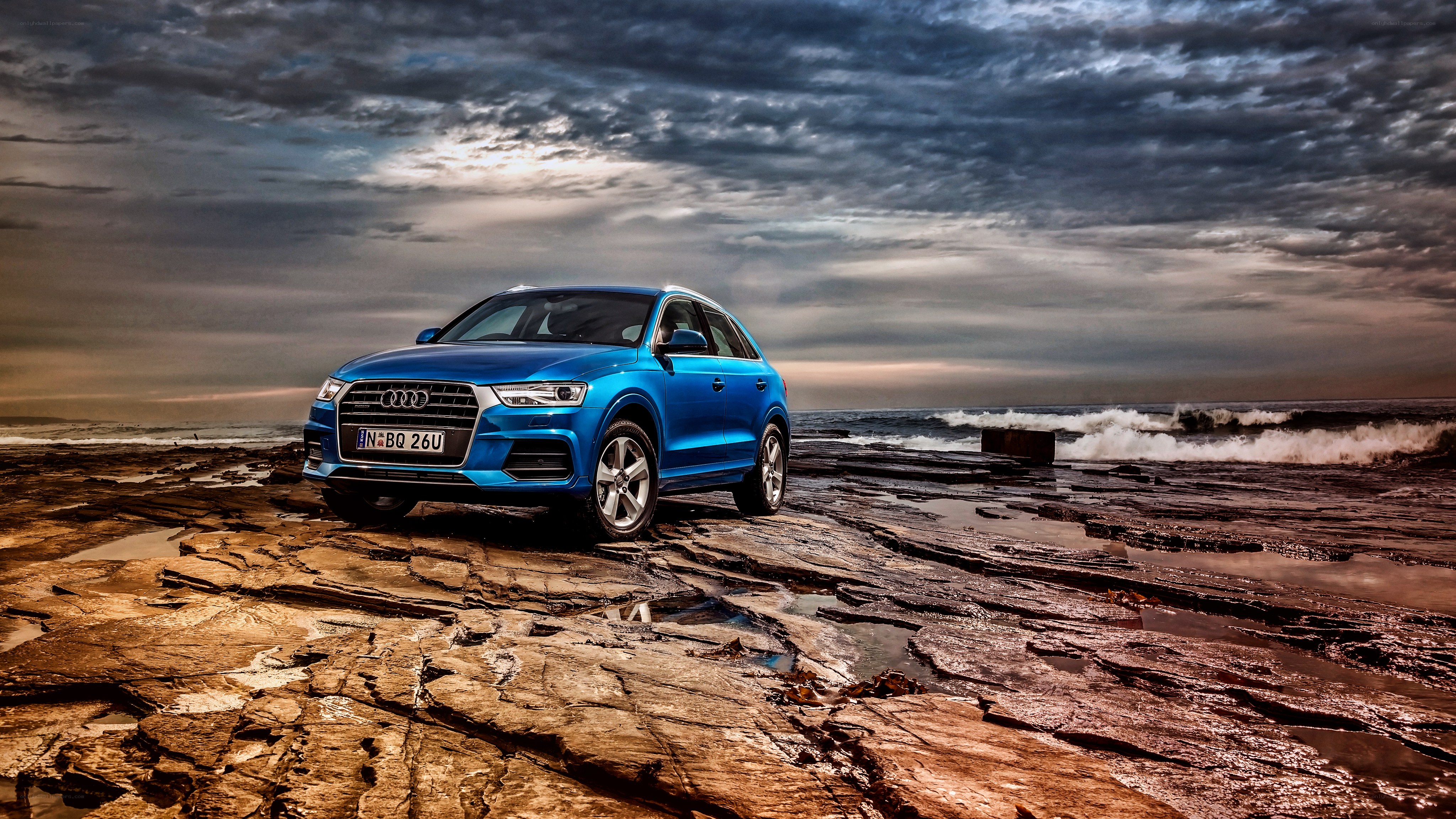Blue Audi on rocky shore