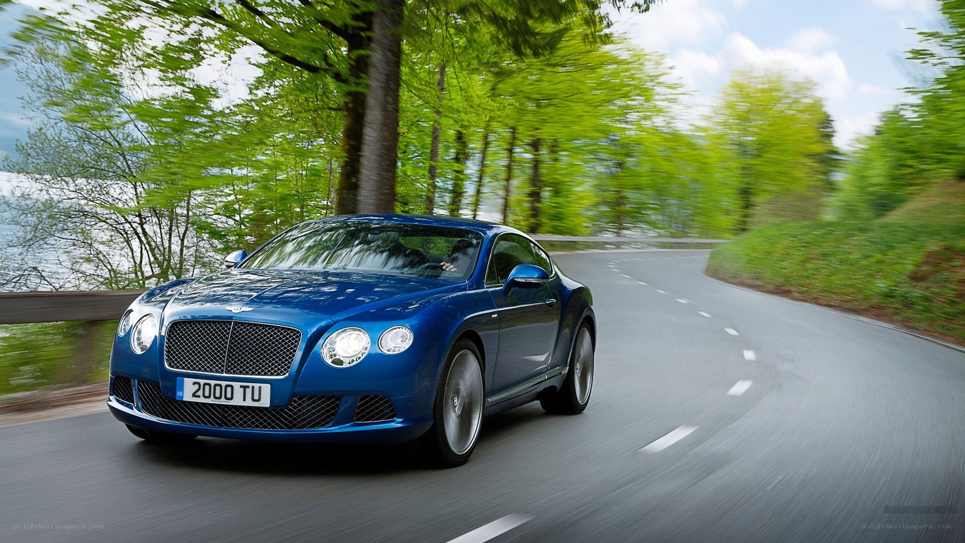 Blue Bentley driving on a road
