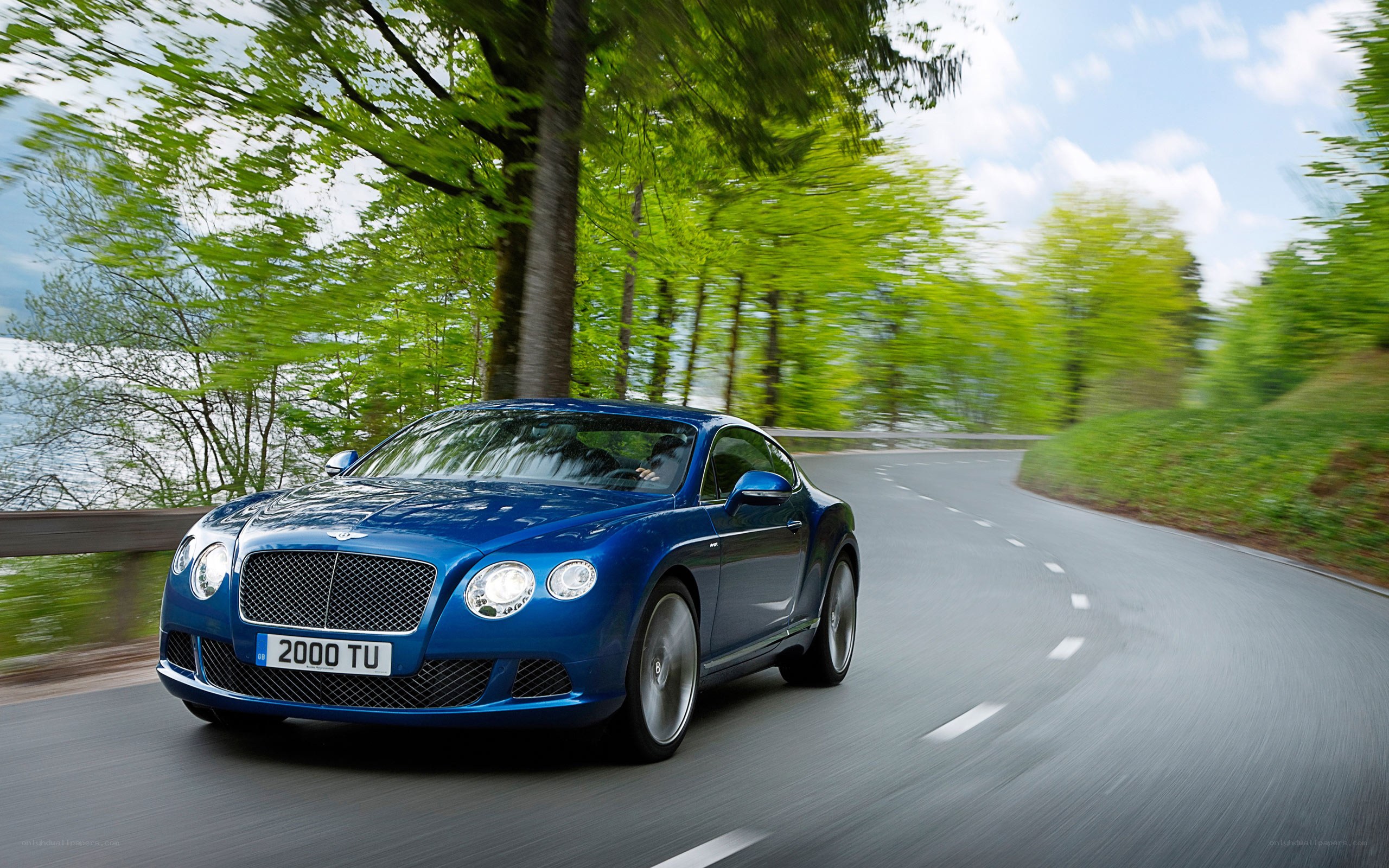 Blue Bentley driving on a road