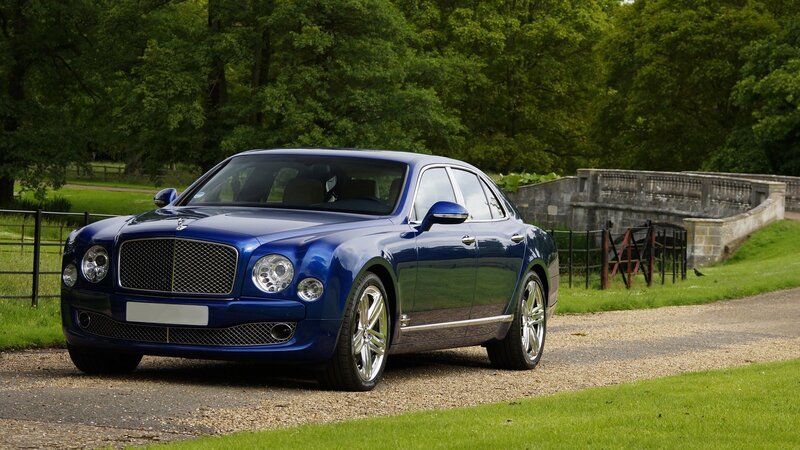 Blue Bentley parked on gravel