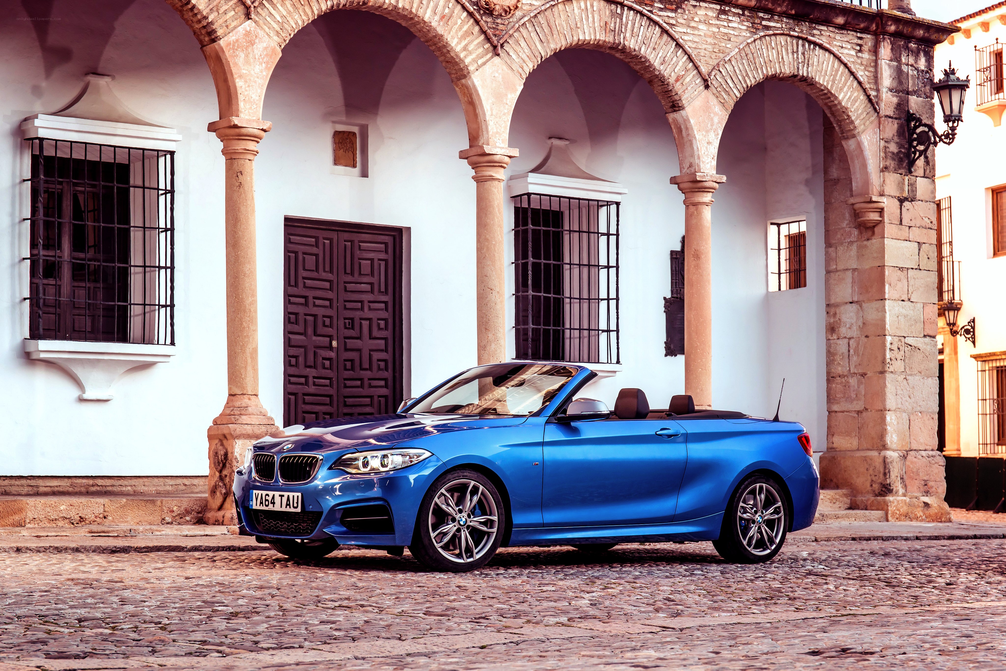 Blue BMW convertible on cobblestone street