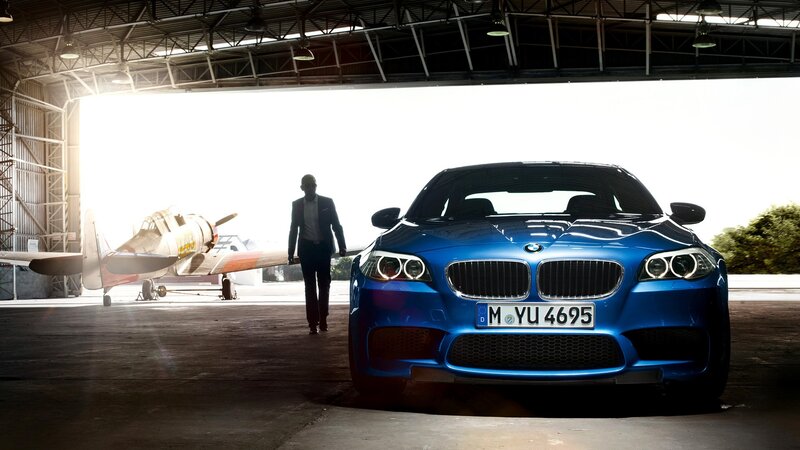 Blue BMW in hangar with airplane
