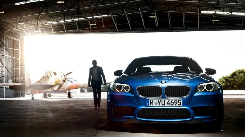 Blue BMW in hangar with airplane