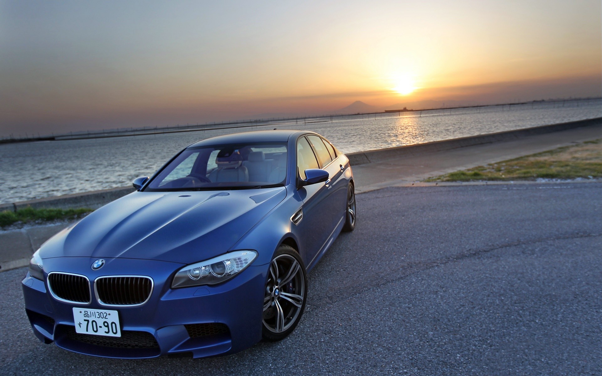 Blue BMW M5 at sunset