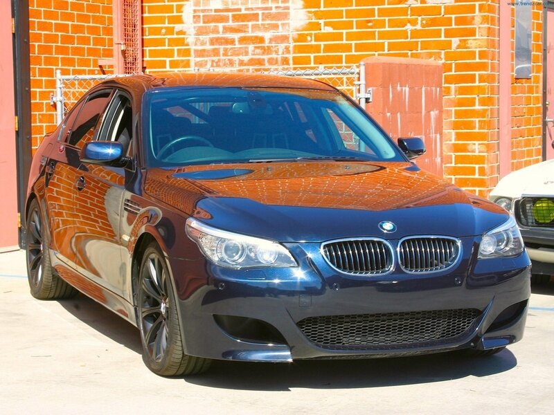 Blue BMW M5 parked in front of brick wall