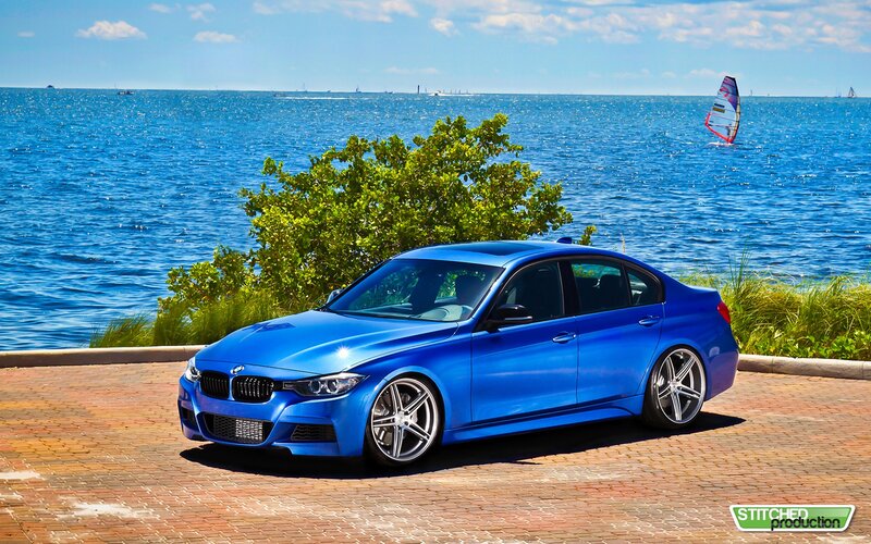 Blue BMW sedan by the water