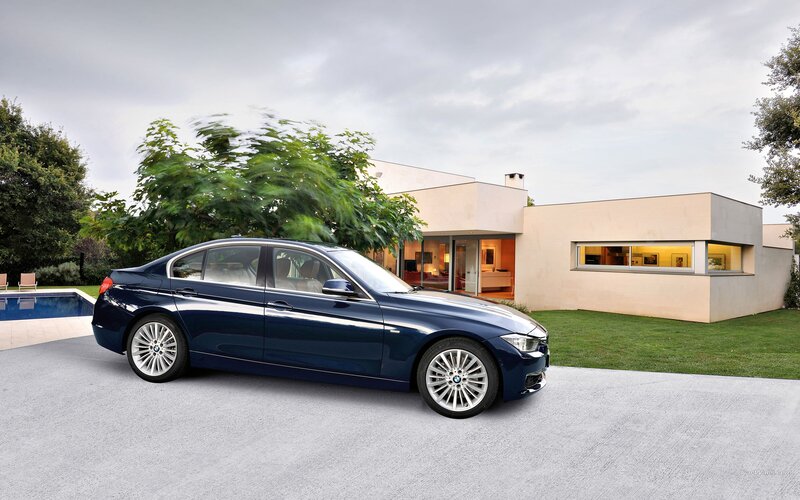 Blue BMW sedan in modern driveway