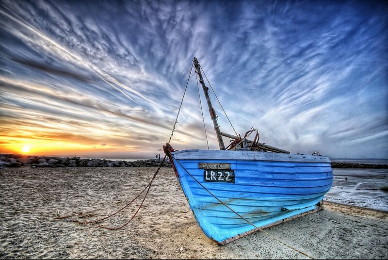 Blue boat on beach at sunset