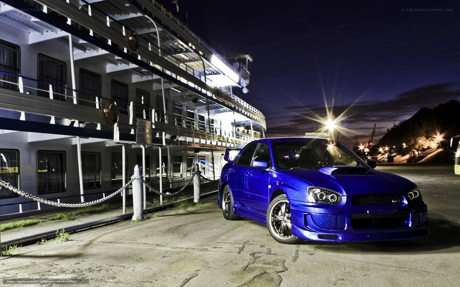 Blue car at night by a ship
