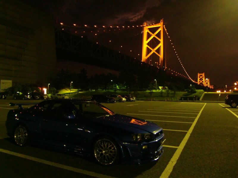 Blue car at night near bridge