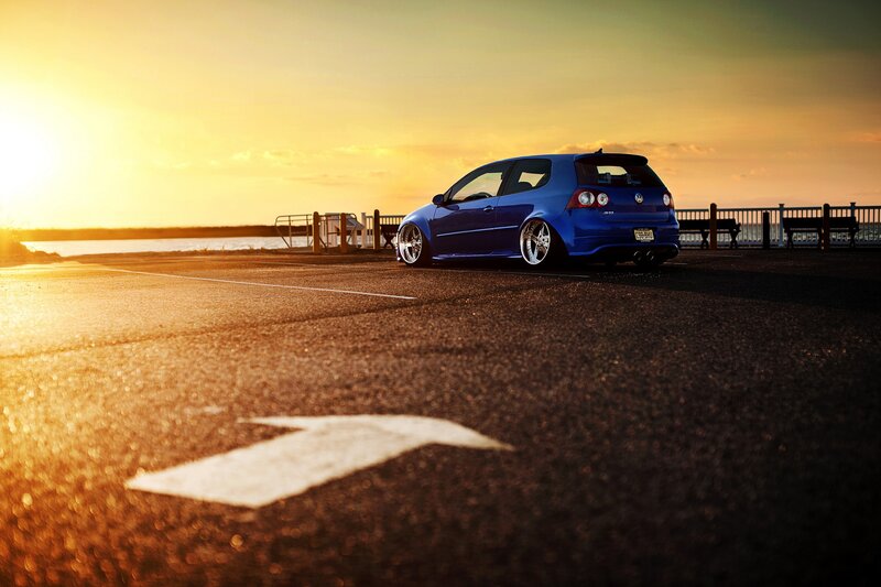 Blue car at sunset by the water
