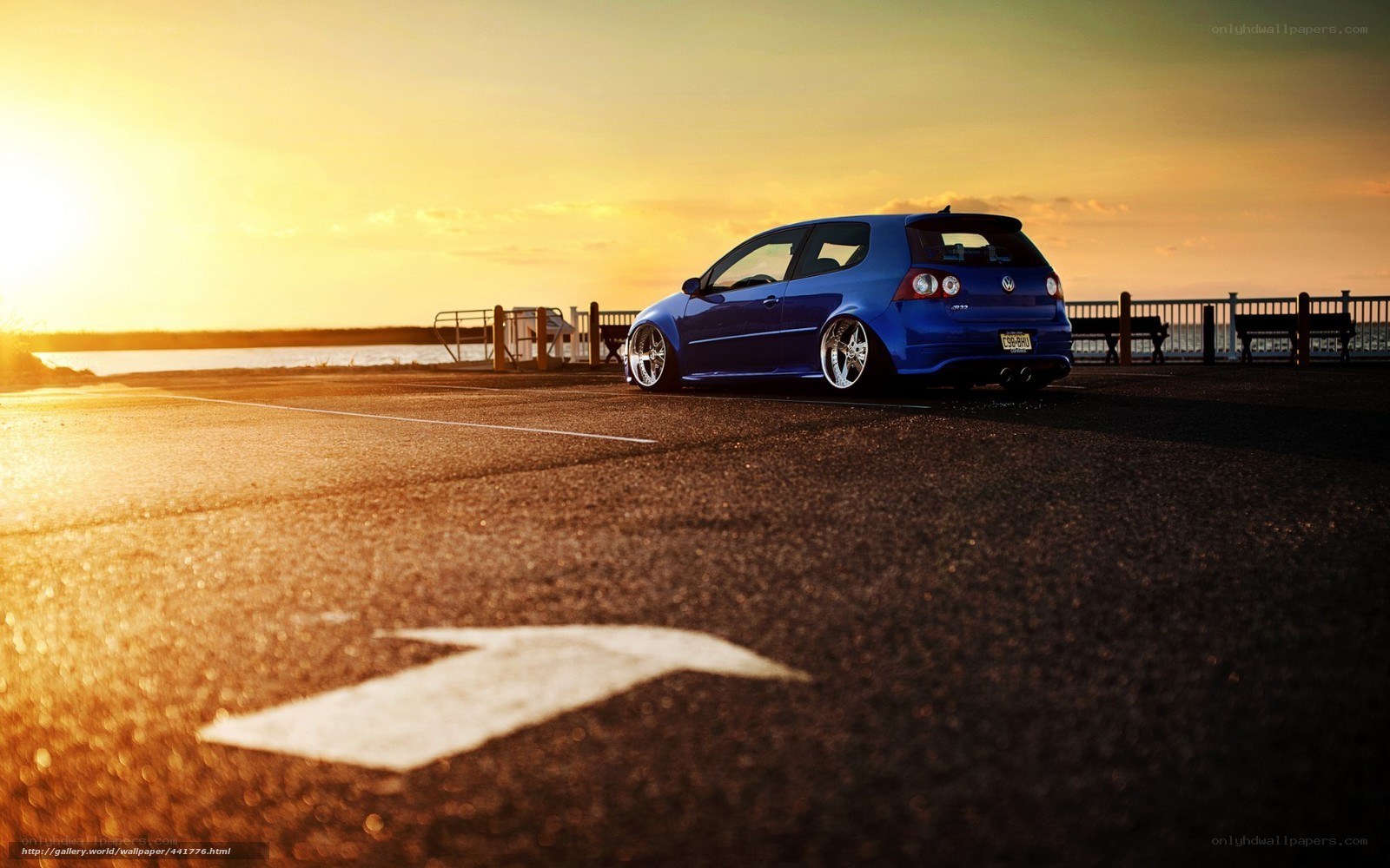 Blue car at sunset by water