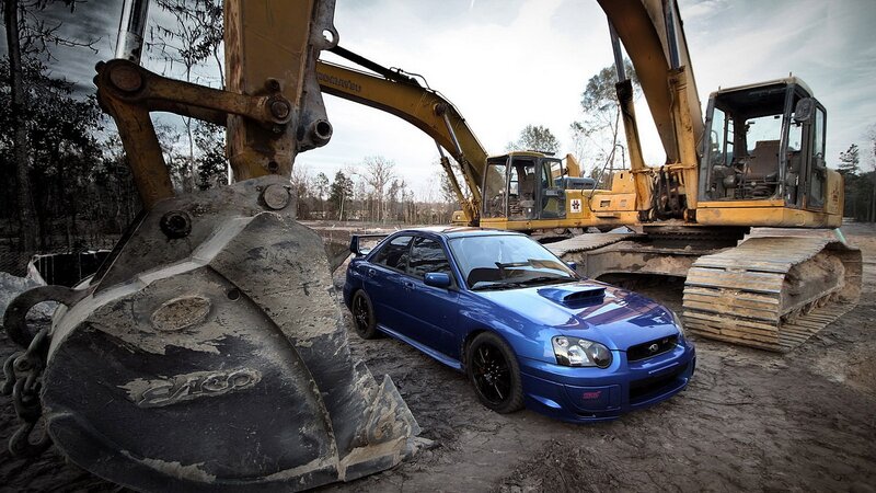 Blue car between excavators