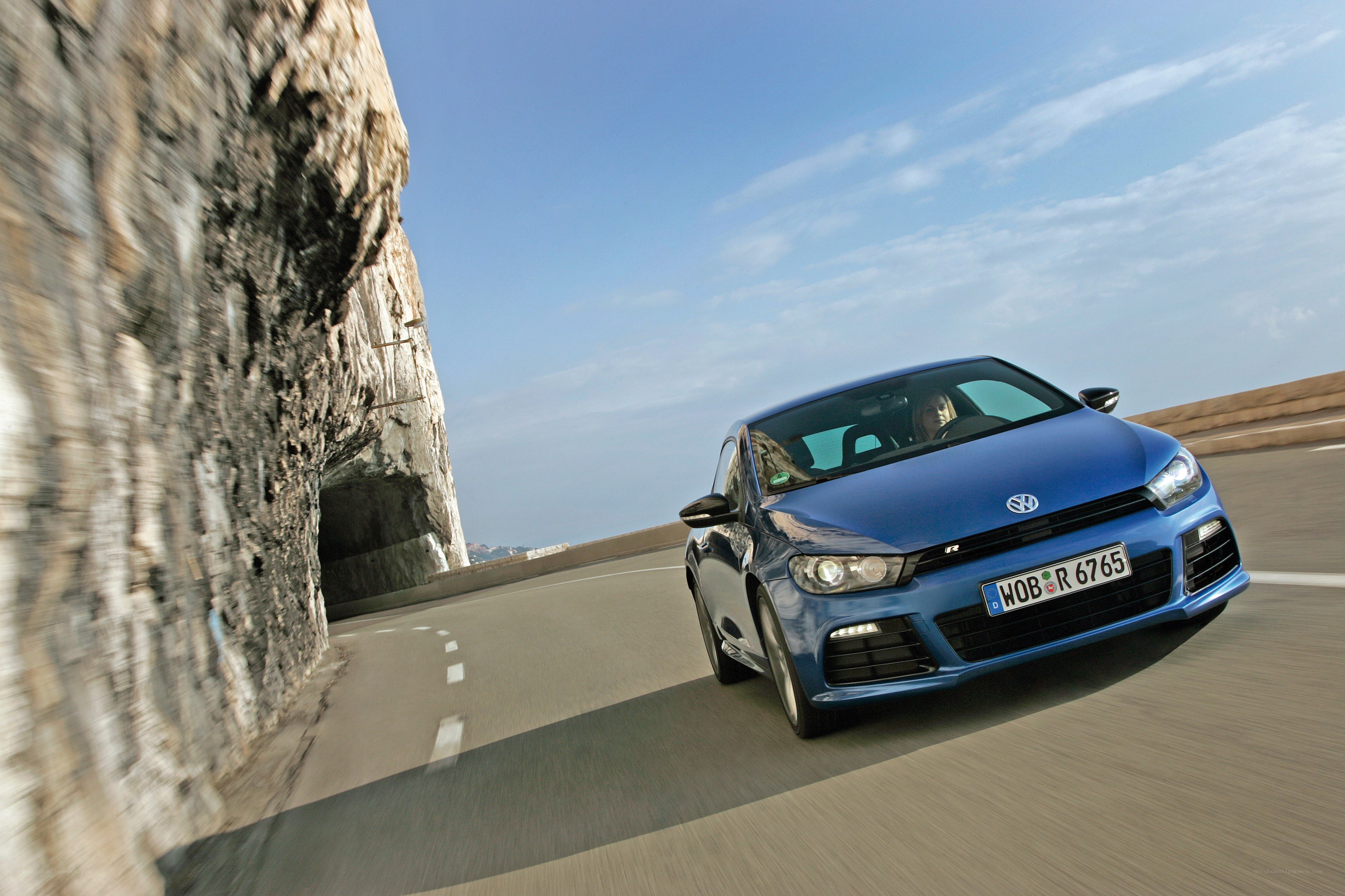 Blue car driving on coastal road