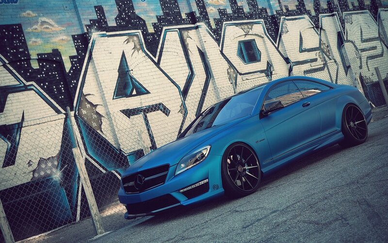 blue car in front of graffiti wall