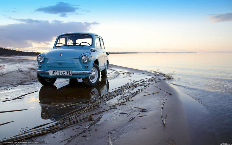 Blue car on beach at sunset