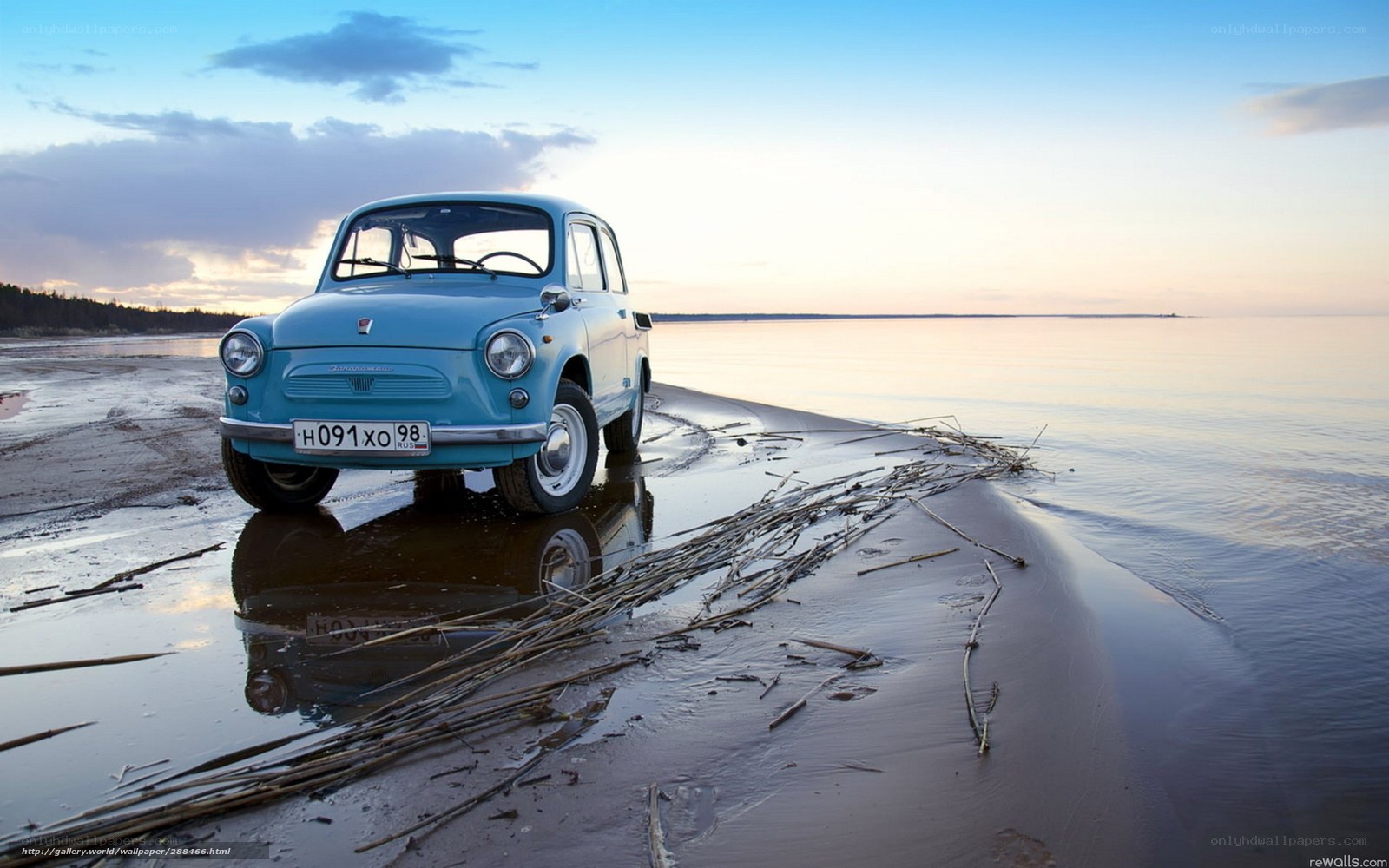 Blue car on beach at sunset