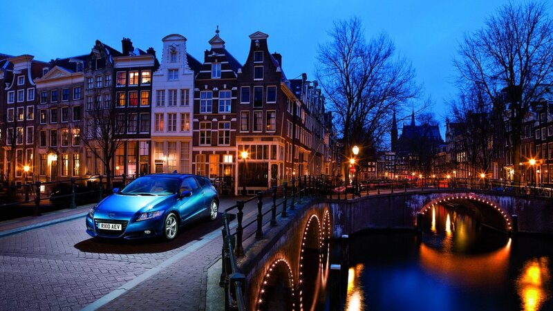 Blue car on canal bridge at dusk