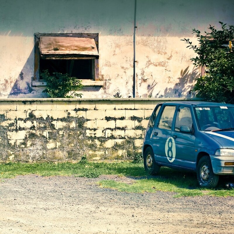 blue car parked by old building