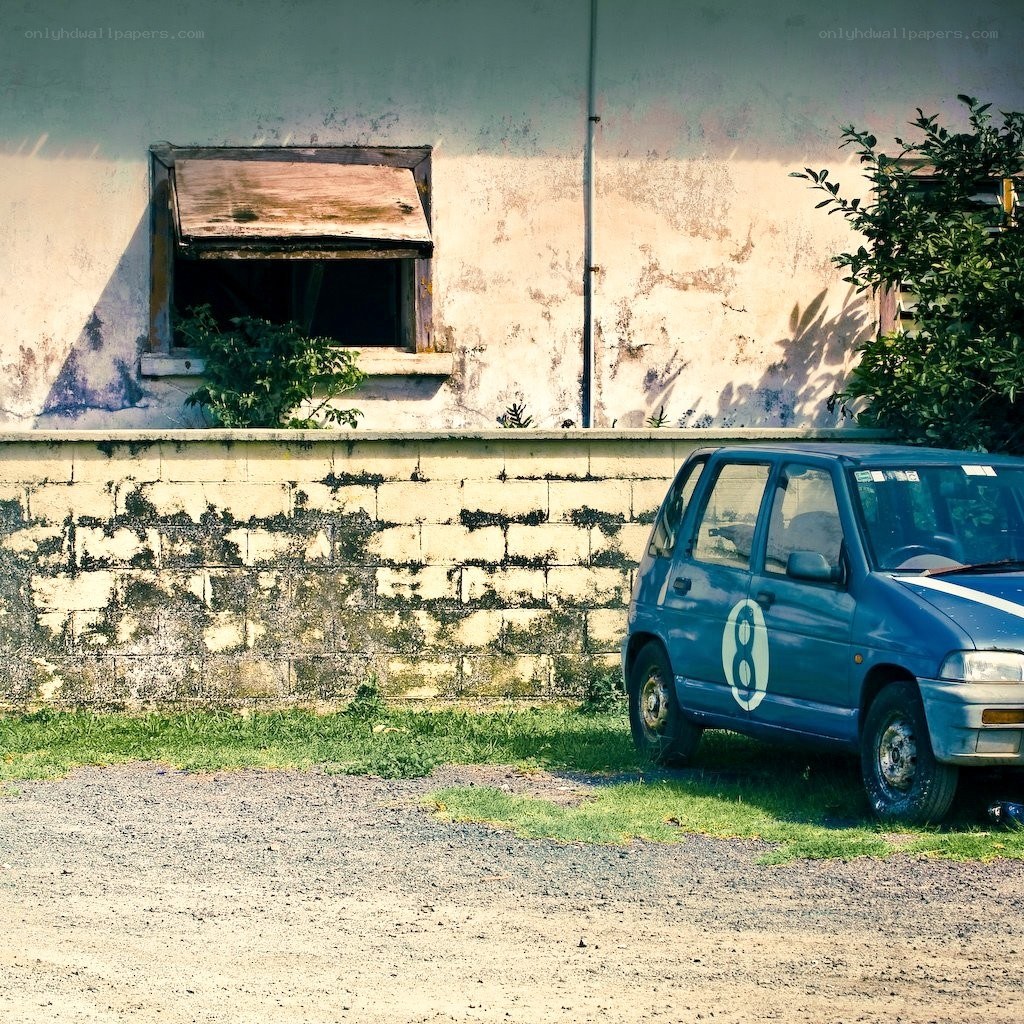 blue car parked by old building