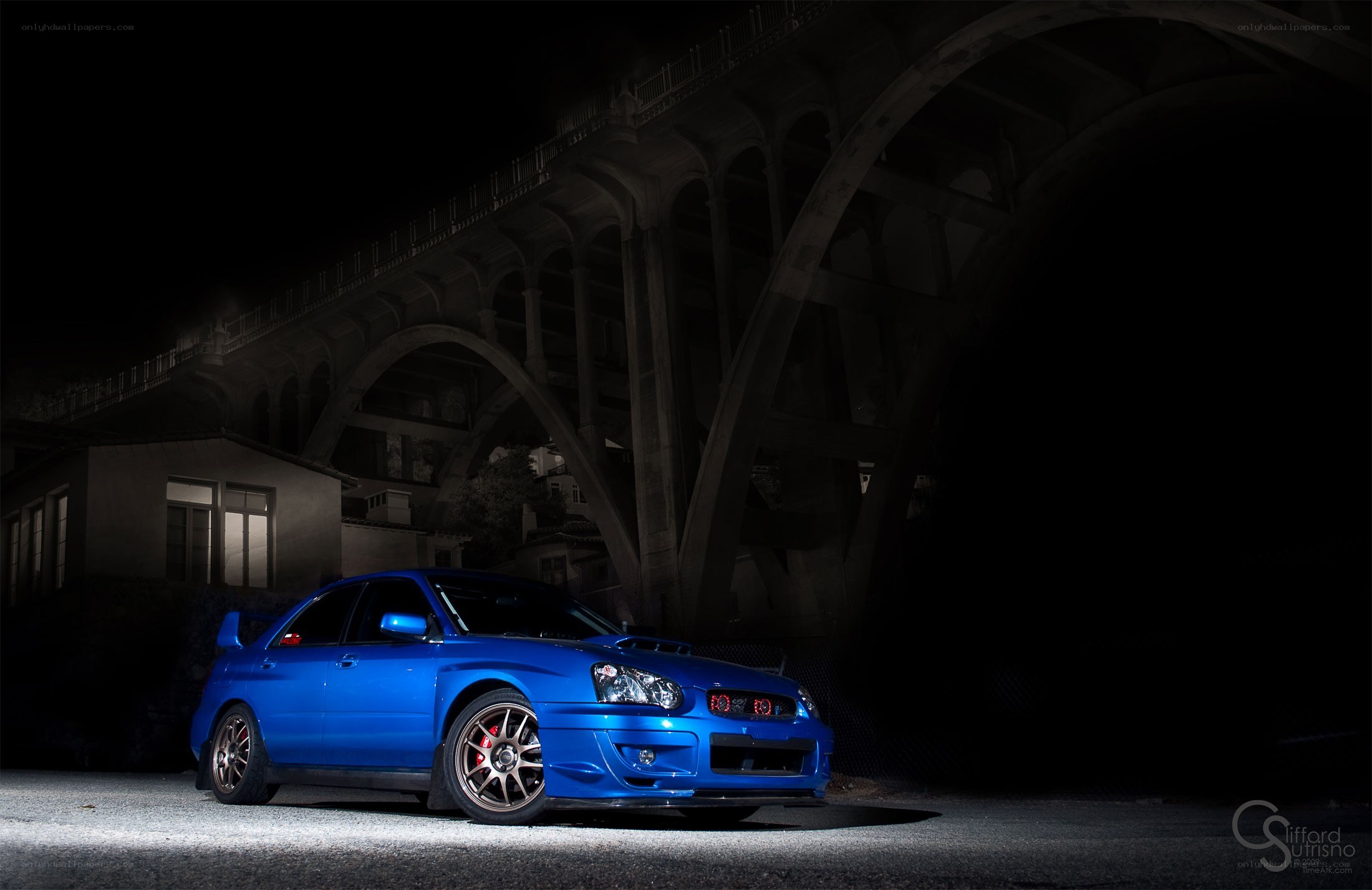 Blue car under a bridge at night