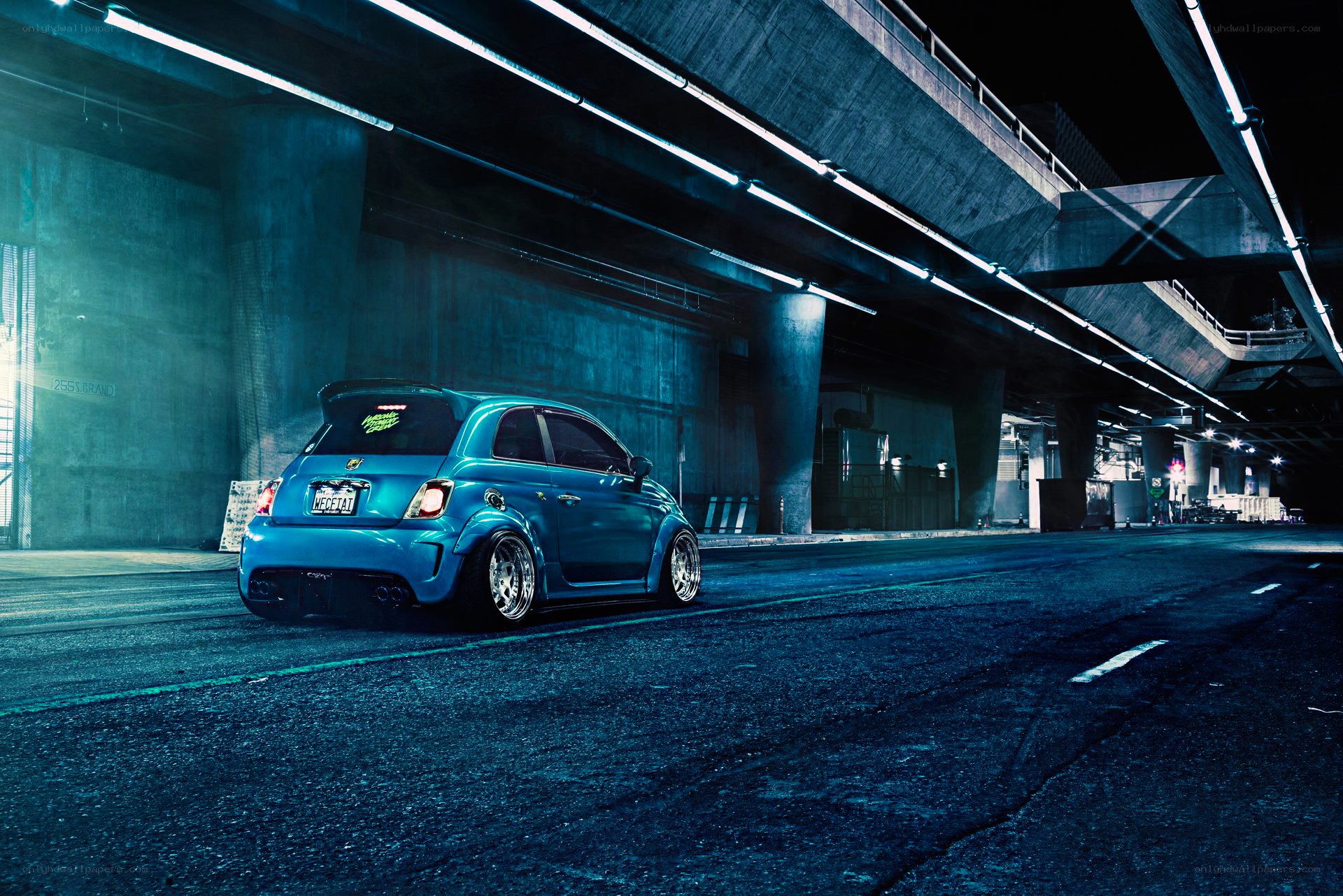 Blue car under highway at night