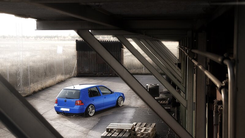 Blue car under industrial structure