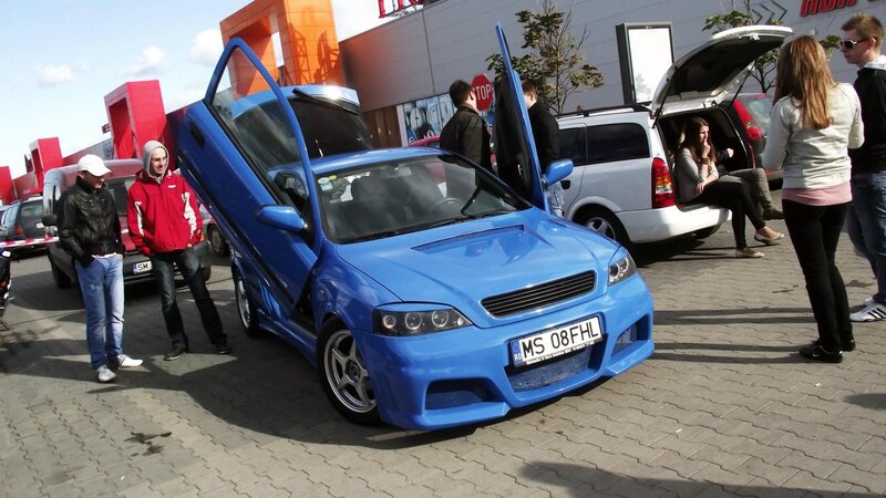 Blue car with open doors at outdoor event